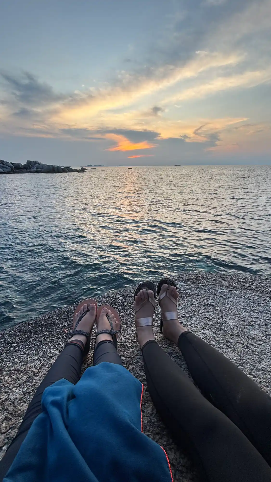 Pasangan traveler menikmati sunset romantis di antara batuan granit Pantai Tanjung Tinggi Belitung