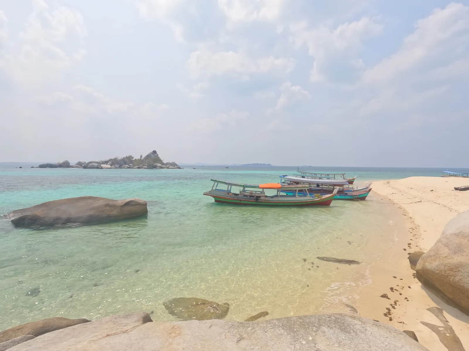 Pemandangan pantai pasir putih dan perahu tradisional di Belitung