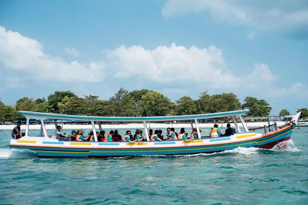 Sekelompok anak muda solo traveler tertawa bersama di atas perahu kayu island hopping Belitung