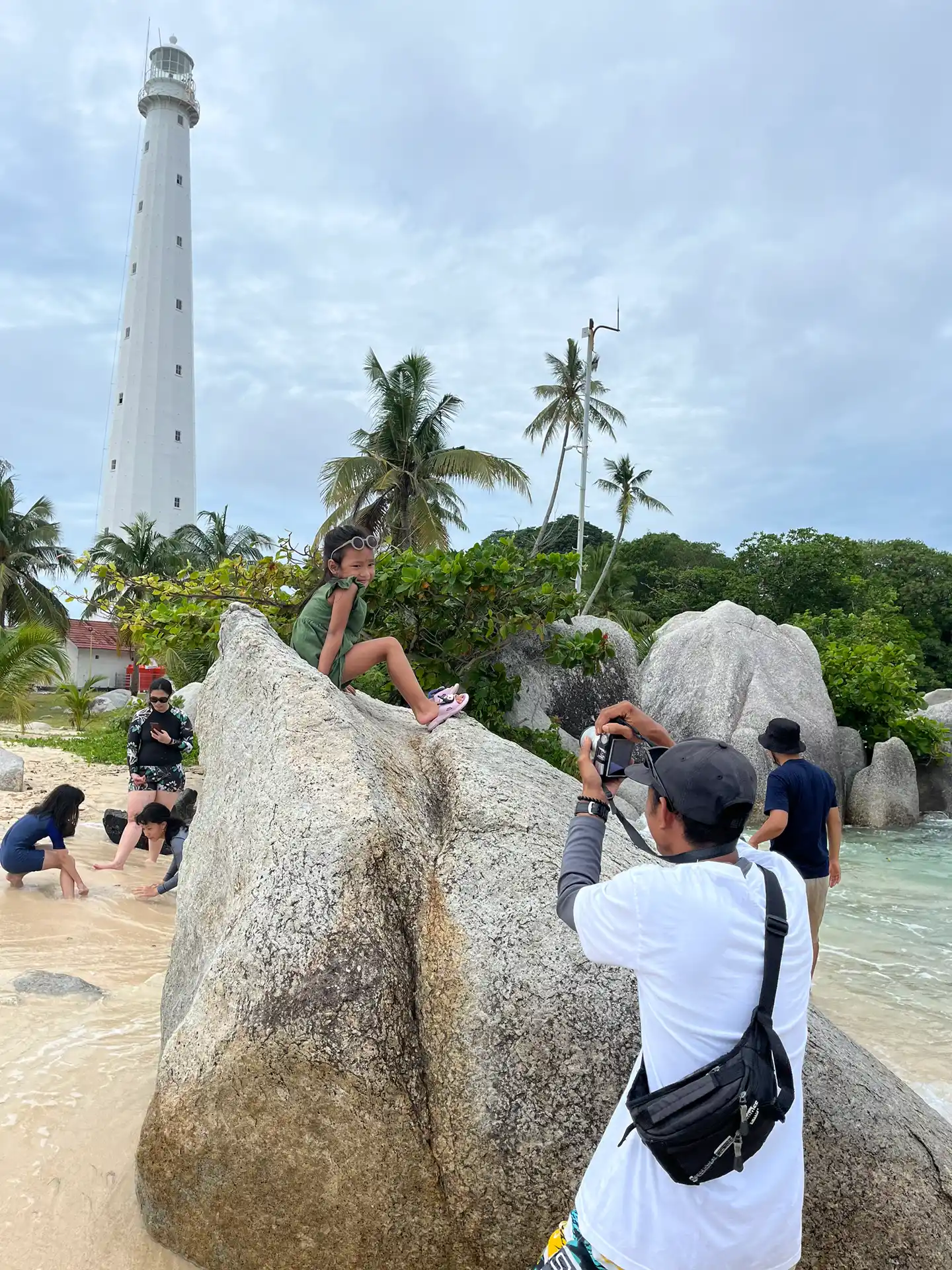 Wisatawan berfoto santai di depan Mercusuar Pulau Lengkuas dengan pemandu profesional